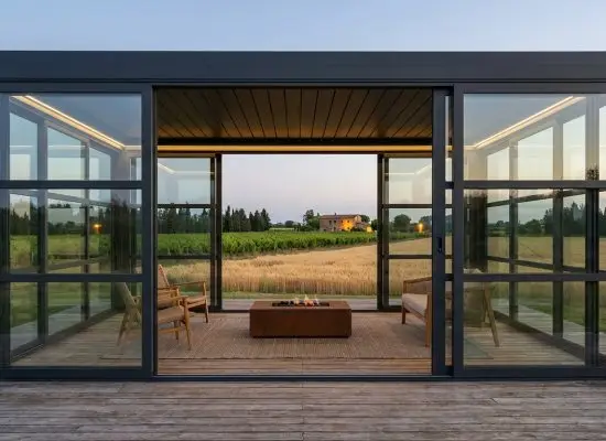 Pergola Bioclimatica Bioeclisse in alluminio antracite con vetrate scorrevoli su terrazza di agriturismo con vigneto